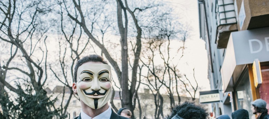 man in black suit jacket wearing black and white mask